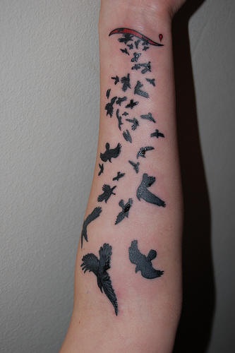 Tatuaggio grande sul braccio gli uccelli