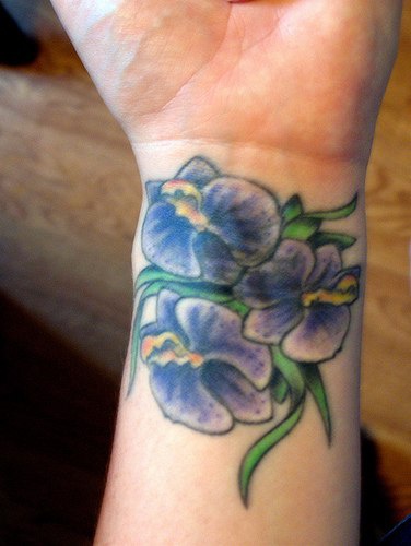 Tatuaggio sul polso i fiori violi verdi