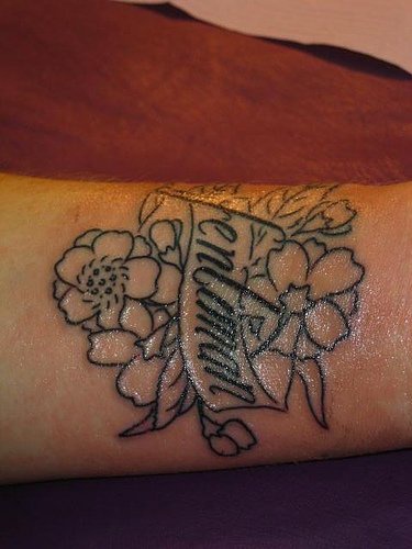 Classic flowers and writings tattoo on wrist