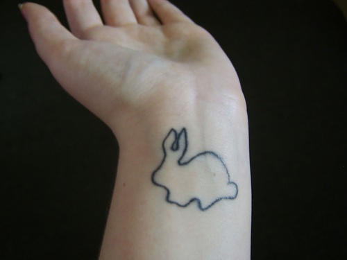 Le tatouage de poignet avec un silhouette de lapin