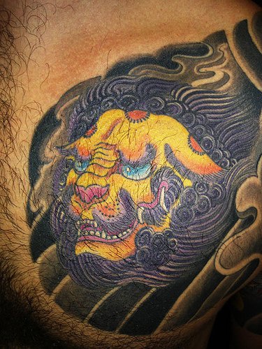 Yellow asian lion chest tattoo