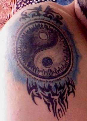 Yin yang tattoo with tribal elements on the shoulder