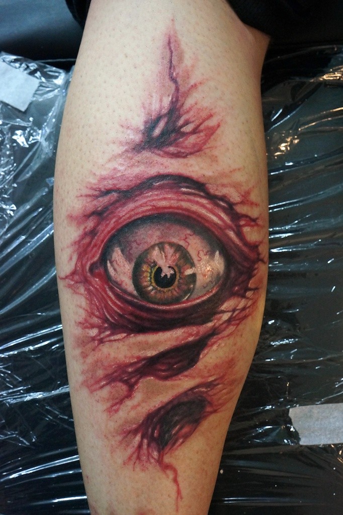 Tatuaje en el brazo, piel rasgada con un ojo asustado