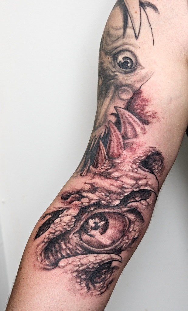Tatuaje en el brazo, dibujo surrealista, ojos, colmillos