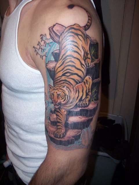 Tattoo of tiger coming down from the cliff