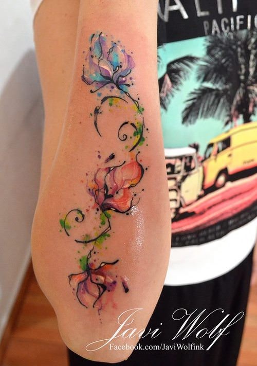Tender elegant colored flowers on vine forearm length tattoo by Javi Wolf in watercolor style