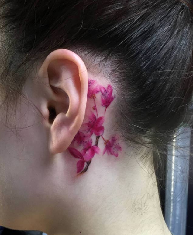 Zarte rosa Blüten elegantes Tattoo hinter dem Ohr