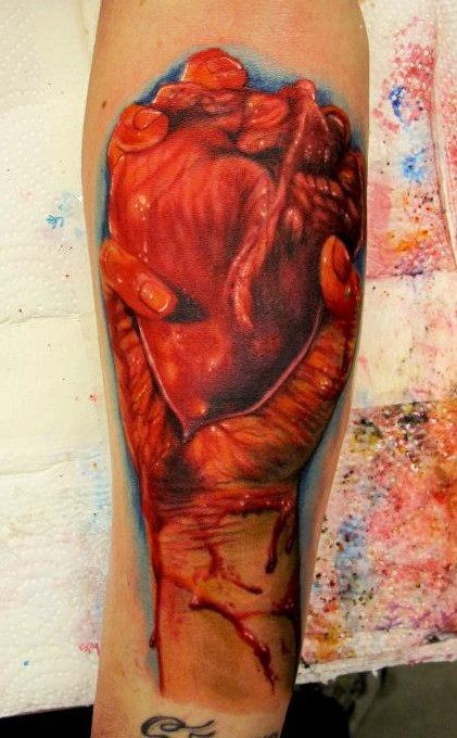 Terrible red heart in hand tattoo by Fabricio Mello