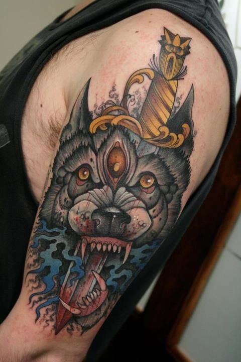 Terrifying colored demonic dog head tattoo on shoulder with bloody dagger