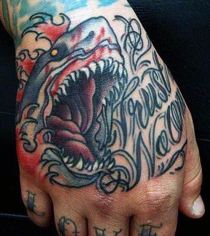 Erschreckender verrückter blutiger Hai im Oldschool Stil farbiges Tattoo auf der Hand mit Schriftzug