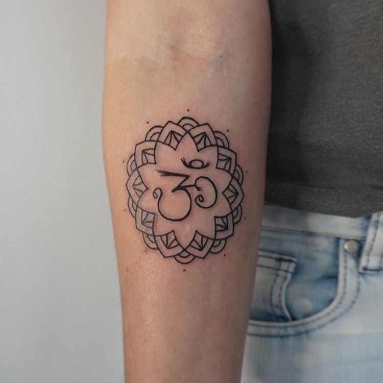 Tatuaje en el antebrazo, símbolo hindú en flor, tinta negra