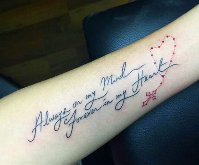 Dünner dunkler schwarzer  Gedenk Schriftzug mit rotem Kreuz auf Kette Unterarm Tattoo