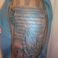 Tatuaje en el brazo, manos que oran con rezo en el pergamino