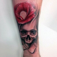 Tatuaje en el antebrazo, cráneo humano y amapola