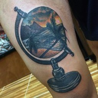 3D like colored little globe stylized with ocean shore and palm tree tattoo on thigh