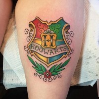 3D like very beautiful colored fantasy Hogwarts emblem tattoo on thigh with flower
