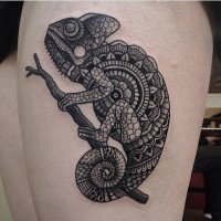 3D like very detailed black ink chameleon tattoo on thigh stylized with tribal ornaments