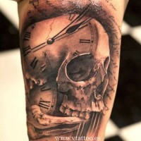 Tatuaje en el brazo,
cráneo humano combinado con reloj y inscripción larga