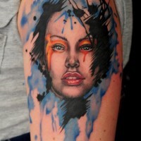 Tatuaje en el brazo,
rostro de mujer atractiva con manchas de pintura