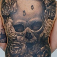 Tatuaje en la espalda completa, cráneo espantoso enorme entre flores