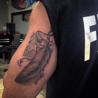 Tatuaje en el brazo,  punta de flecha con pluma gris