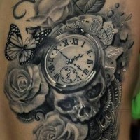 Tatuaje en el costado,  reloj antiguo con cráneo humano y flores