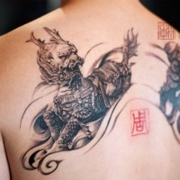3D style very detailed black and white Asian demons tattoo on upper back combined with tiny red symbol