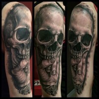 Tatuaje en el brazo, cráneo humano volumétrico con mano de hombre
