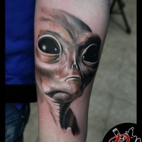 Alien face tattoo on arm