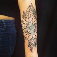 Tatuaje en el antebrazo, flor mandala con hojas