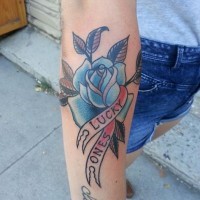 Tatuaje en el antebrazo, rosa americana y cinta con cita