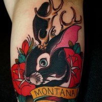 Awesome old school hare with deer hornes and ribboned lettering tattoo on arm