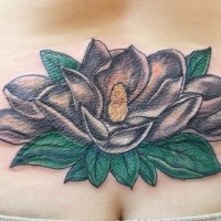 Tatuaje en la espalda baja, 
magnolia negra con hojas verdes