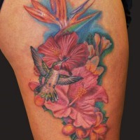 Bright-colored hawaiian flowers and bird tattoo on thigh