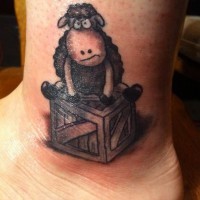 Cartoon sheep sitting on wooden box tattoo on foot