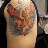 Colored griffin on blue background tattoo for men on upper arm