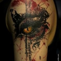 Colored trash polka style upper arm tattoo of demonic eye and lettering