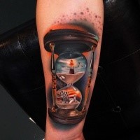 Tatuaje colorido de reloj de arena en el brazo