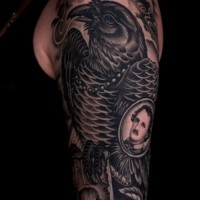 Cool black raven with Edgar Poe portrait tattoo on upper arm