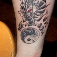 Cooles Tattoo von dunklem Drache mit roten Augen und Yin Yang Mandala am Unterarm