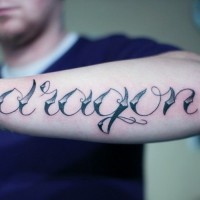 Tatuaje en el antebrazo, palabra dragón de letra preciosa