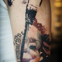Creepy trash polka style upper arm tattoo of clown face with lettering