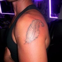 Curled white feather tattoo on shoulder