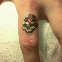 particolre piccolo cranio femminile con fiore tatuaggio su indice