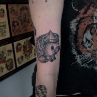 Cute smiling black-and-white hedgehog tattoo on arm
