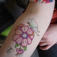 Cute womens pink flower and blue butterfly tatoo on forearm