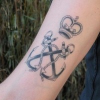 Double-crossed black-and-white anchors with crown on top tattoo on forearm