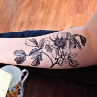 Exiting black-ink vintage flower on stem tattoo on arm