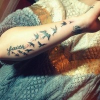 Tatuaje en el antebrazo, bandada de aves y palabra fe