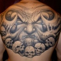 Gray washed style upper back tattoo of monster face wtih skulls